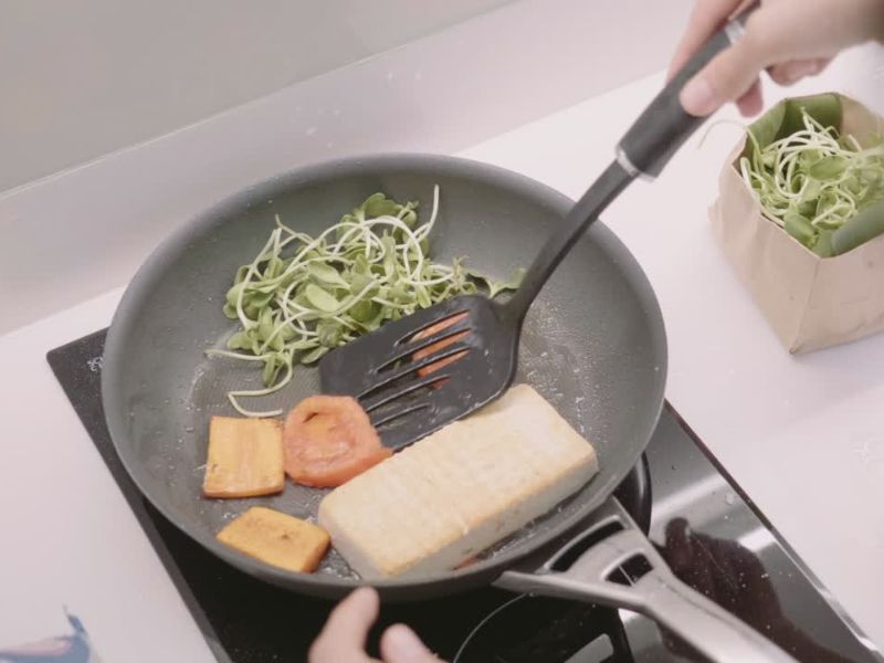 osoba sprema u teflonskom tiganju tofu sir sa povrćem