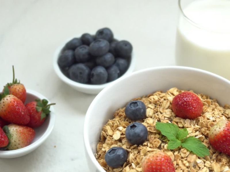 na stolu postavljene jagode, borovnice, musli i biljno mleko