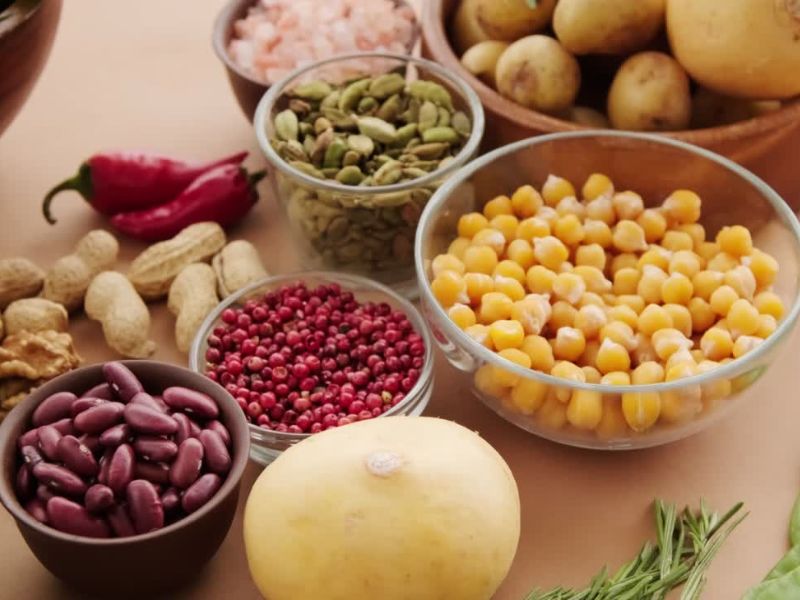 na drvenom stolu postavljena veganska hrana, leblebija, krompir, paprika, pasulj, orašasti plodovi