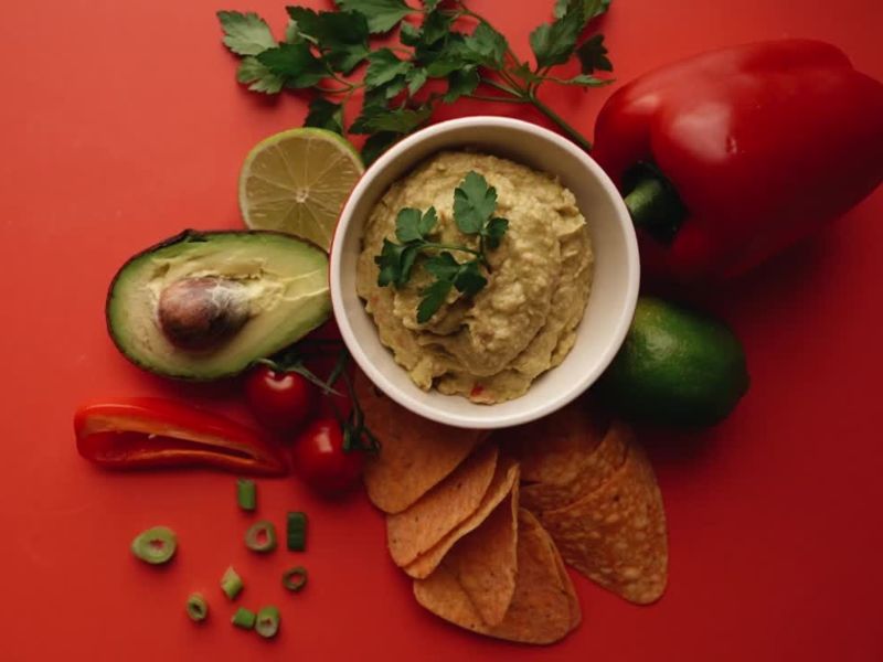 činija puna veganskog namaza, pored avokado, paprika, tortilje i peršun